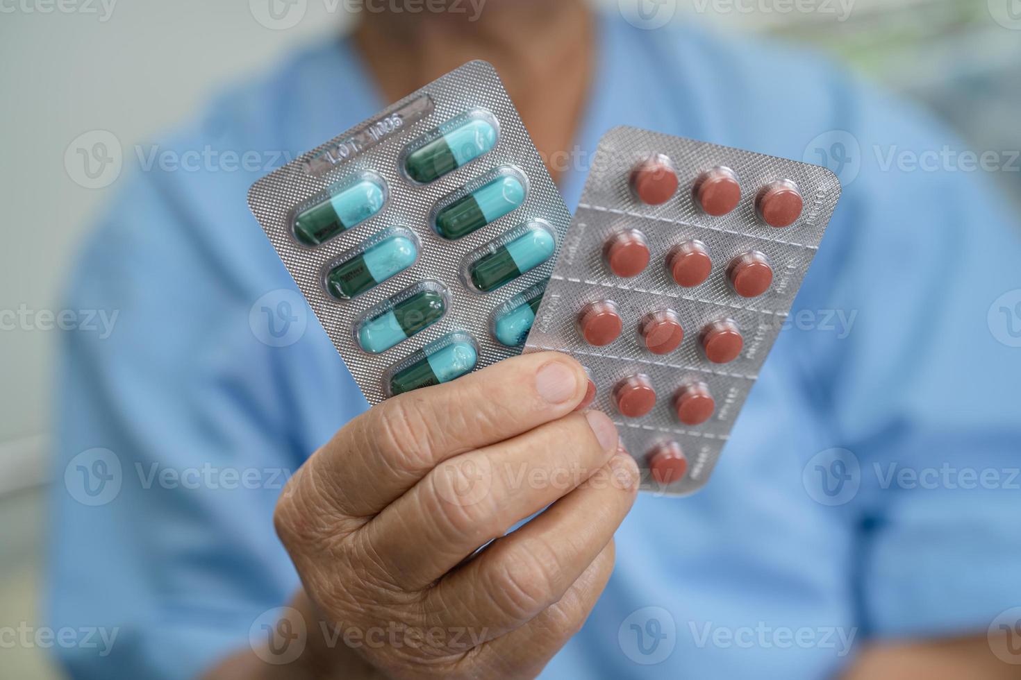 asiatisk senior eller äldre gammal dam kvinna patient håller antibiotika kapsel piller i blisterförpackning för behandling infektion patient på sjukhus, apotek apotek koncept. foto