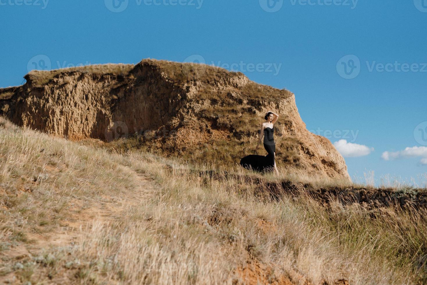 lång flicka modell i en svart klänning på de berg kullar foto