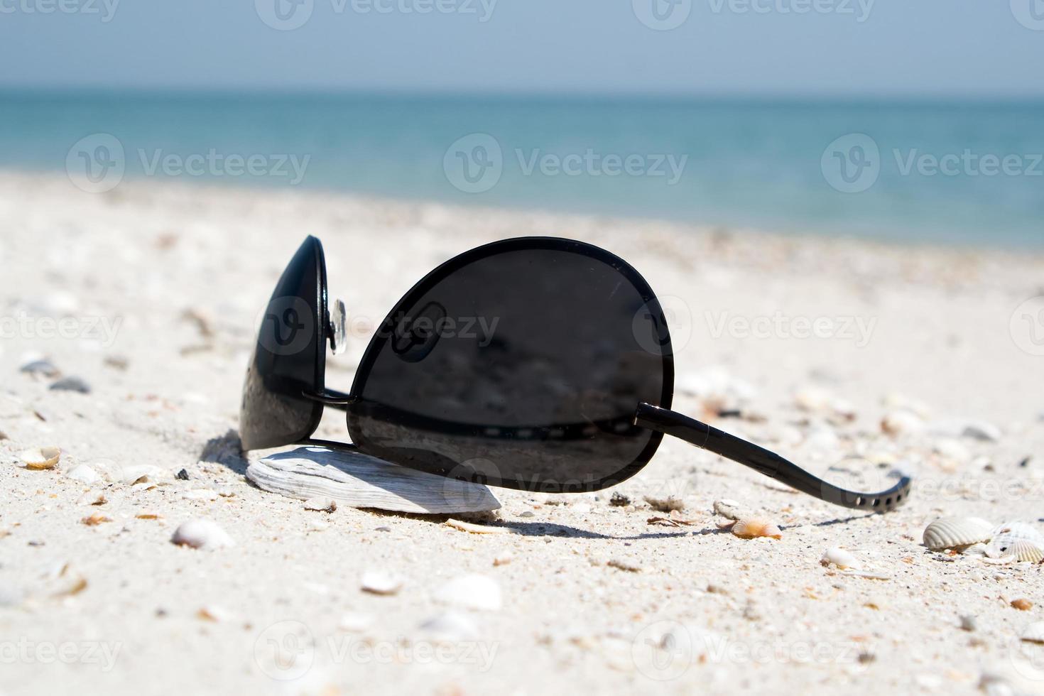 de svart solglasögon liggande på en strand foto