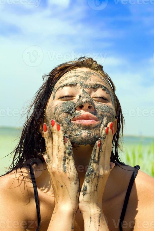kvinna med lera ansiktsbehandling mask foto