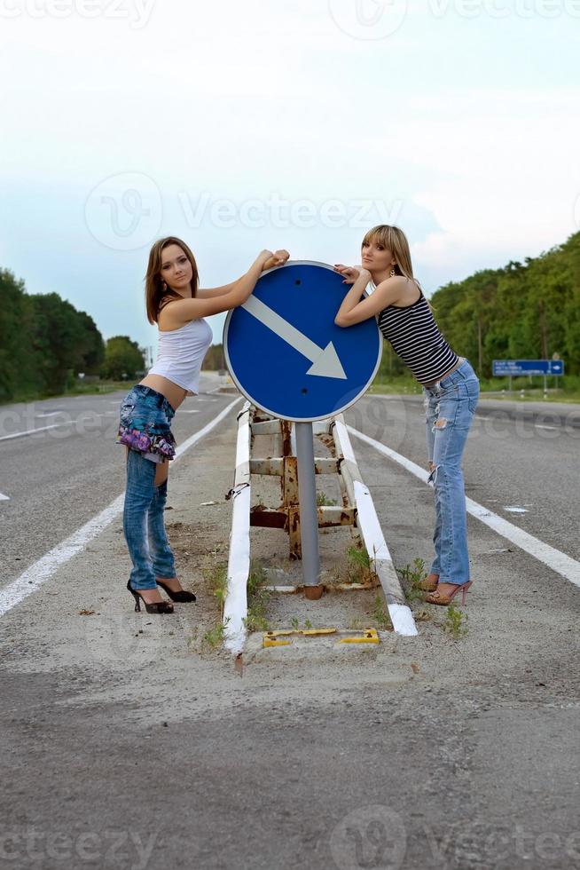 två Söt flickor stå på en väg foto