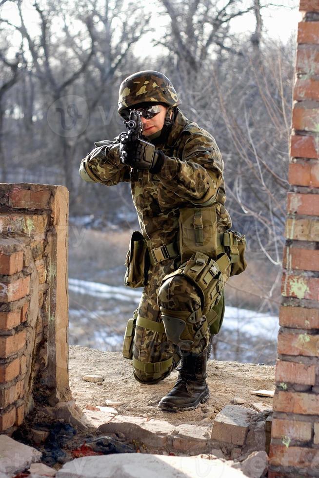 soldat Sammanträde nära vägg med en pistol foto