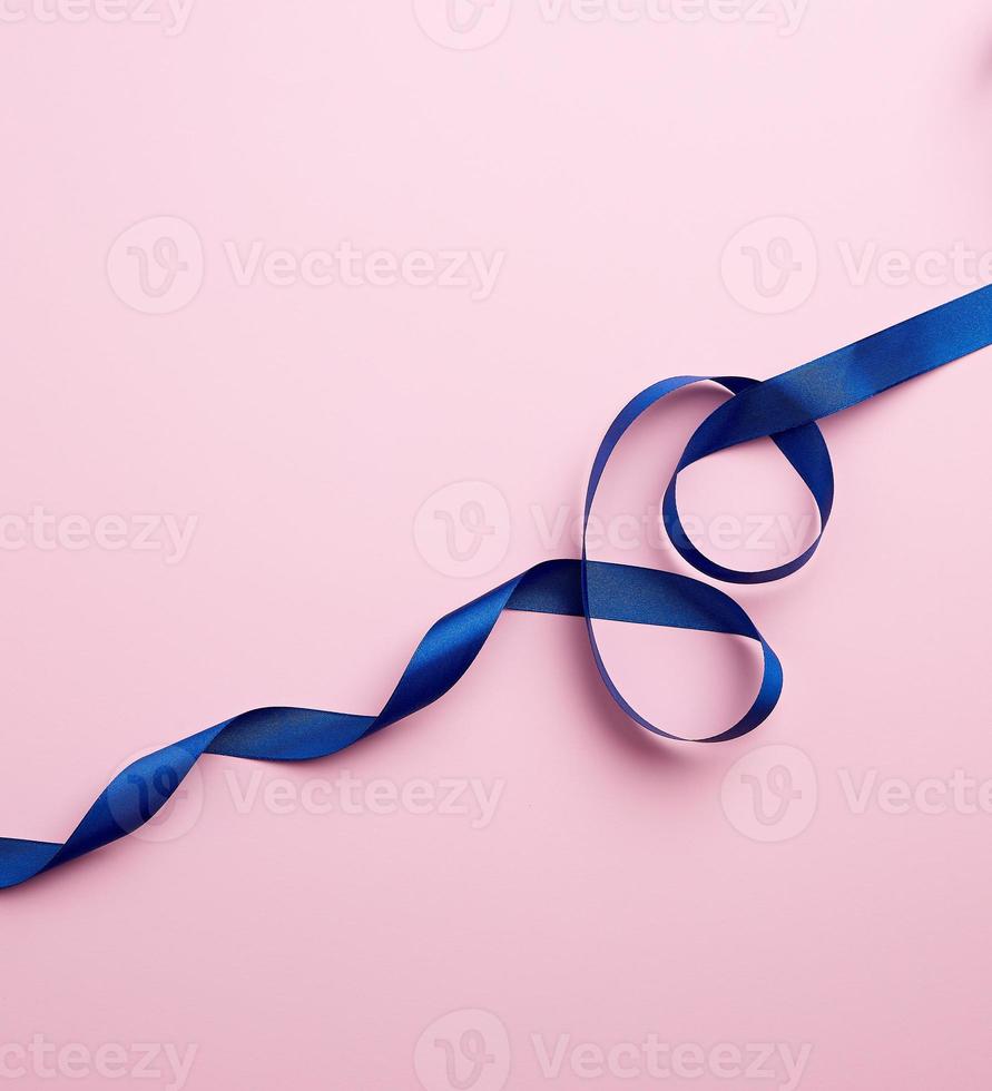 blå silke tunn band vriden på en rosa bakgrund foto