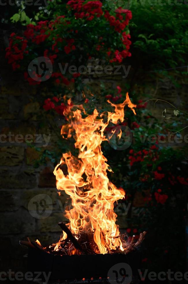 brinnande ved i en metall utegrill och en hög orange flamma foto