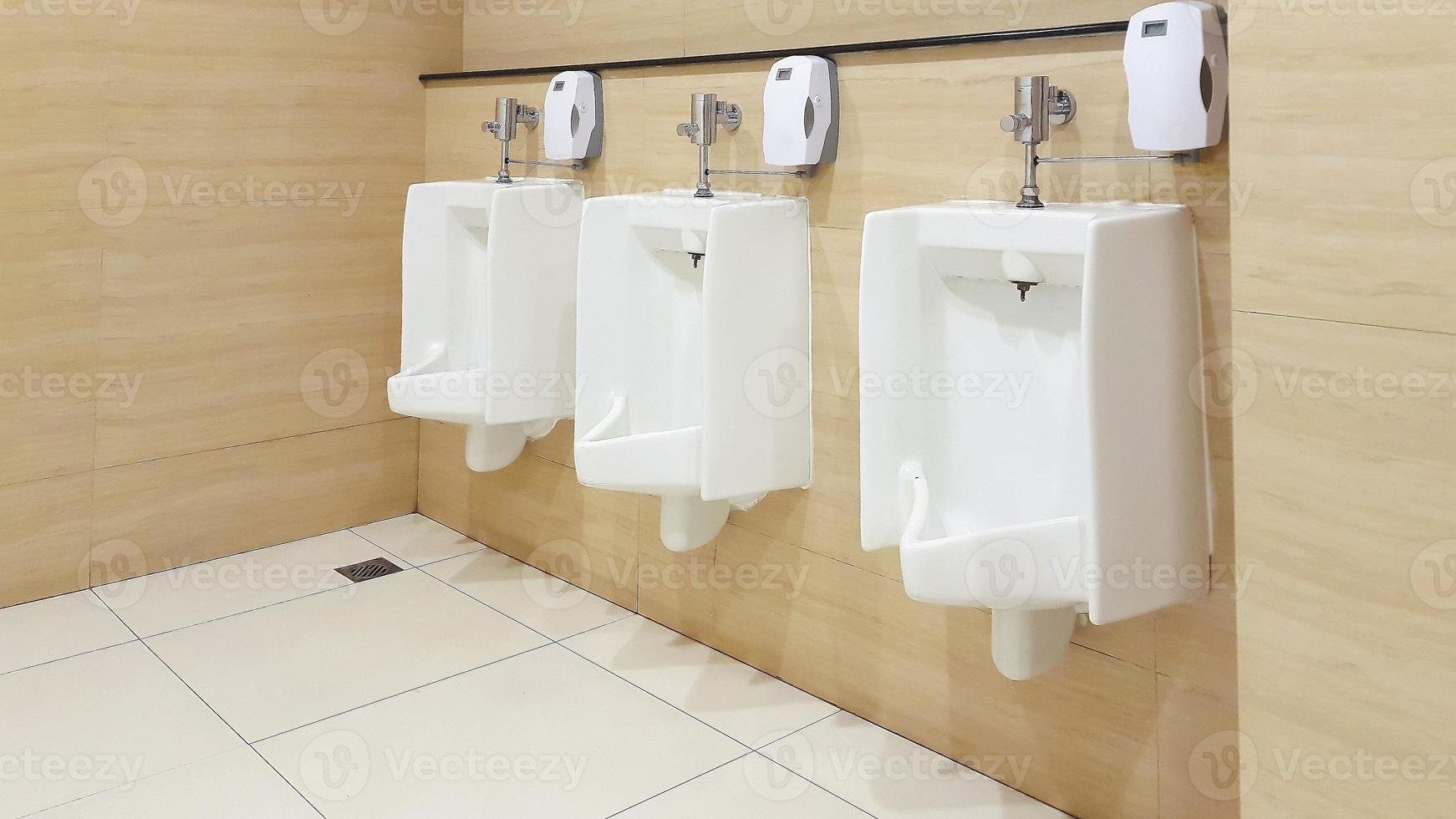 rad av urinoarer män offentlig toalett. stänga upp vit urinoarer i herr- badrum. foto