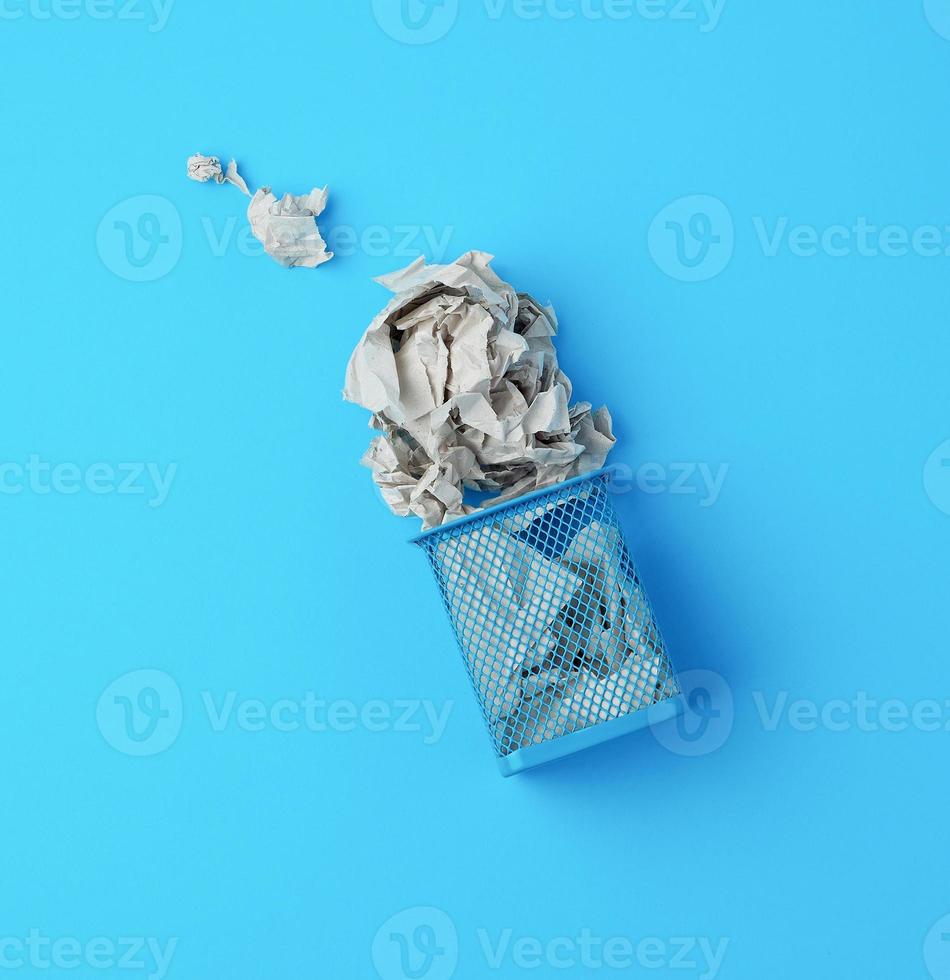 upphävde blå metall korg med skrynkliga bitar av papper foto