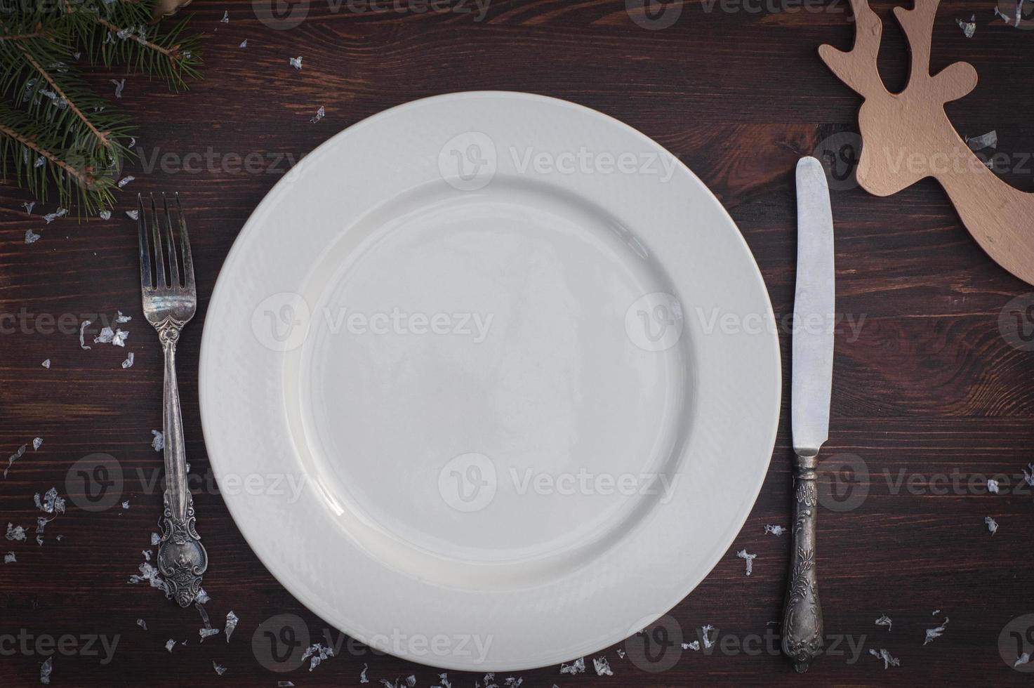 vit tallrik med silver- kniv och gaffel på brun trä- yta jul tabell miljö foto