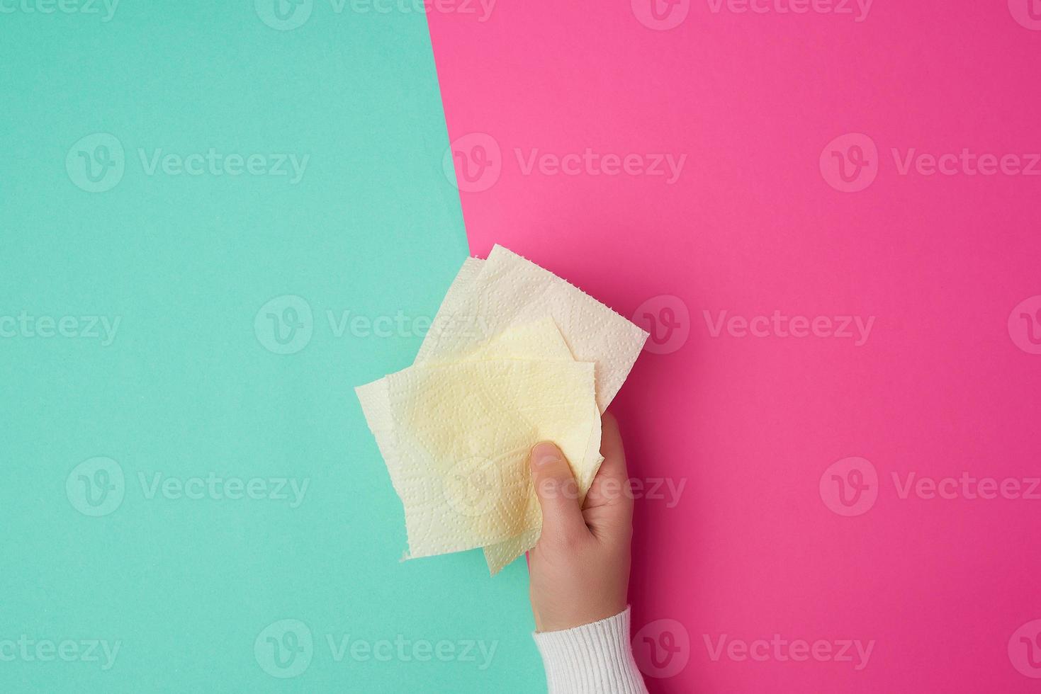 gul toalett papper i kvinna händer, trasig bitar på en färgad bakgrund foto