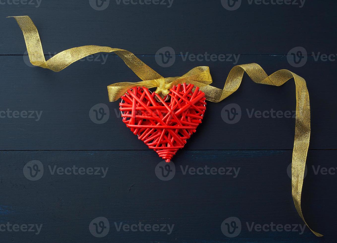 röd korg- dekorativ hjärta hängande på gyllene silke band foto