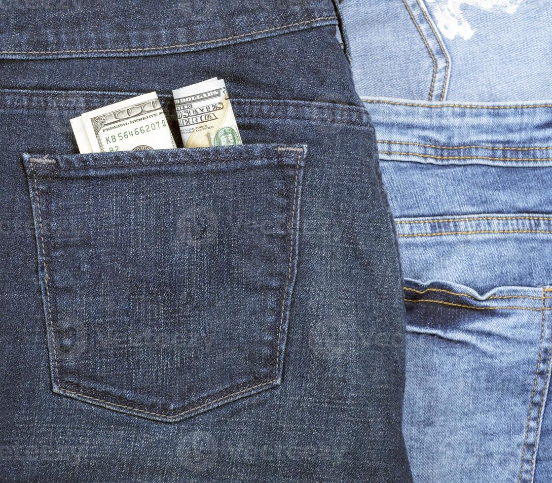 sedlar av de amerikan dollar i de tillbaka ficka av blå jeans foto