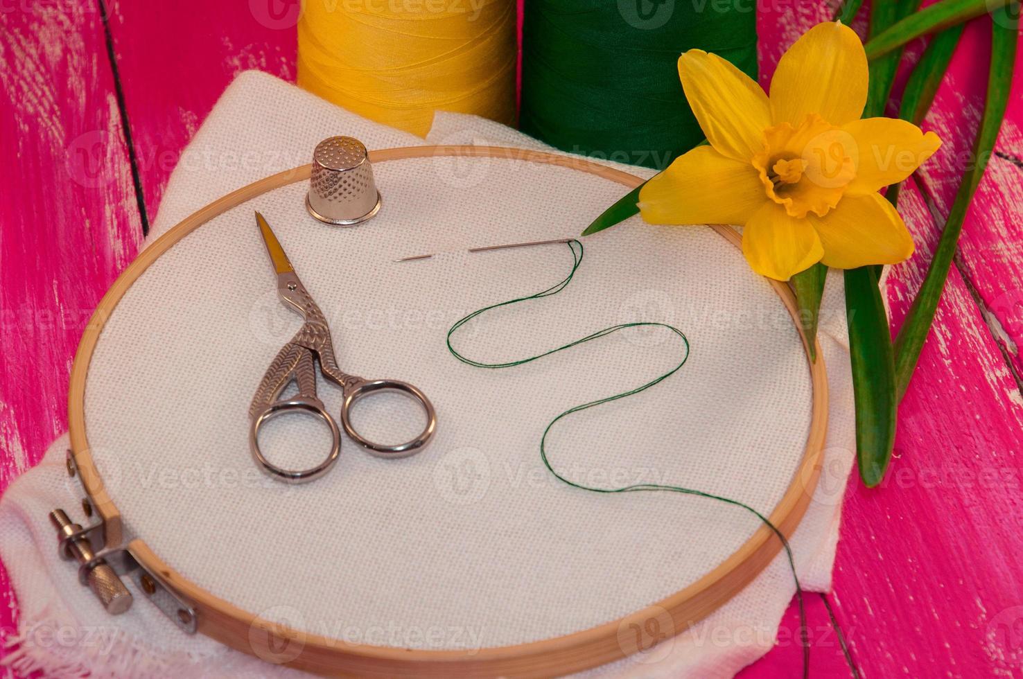 vit tyg i de trä- broderi ram för handarbete på rosa trä- bakgrund foto