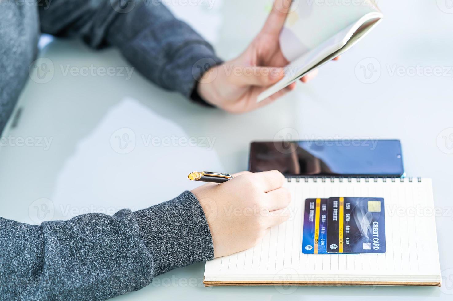 kvinna skriver på anteckningsbok med kreditkort och smartphone skrivbord foto