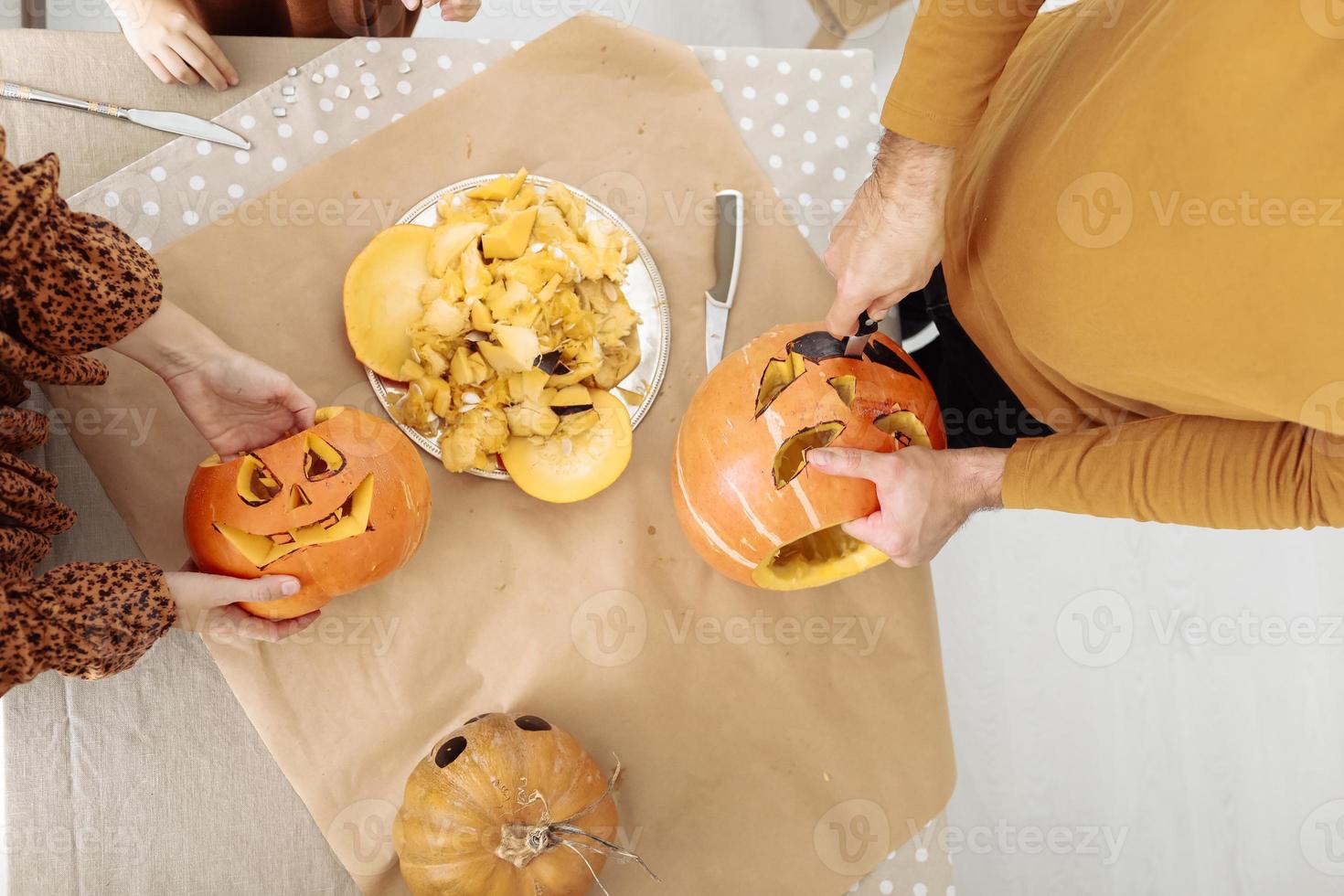 ung par man och kvinna på kök på Hem framställning Pumpalykta framställning för halloween, skärande pumpa. skärande ut ansikten från en färsk pumpa. framställning för de halloween fest firande. foto