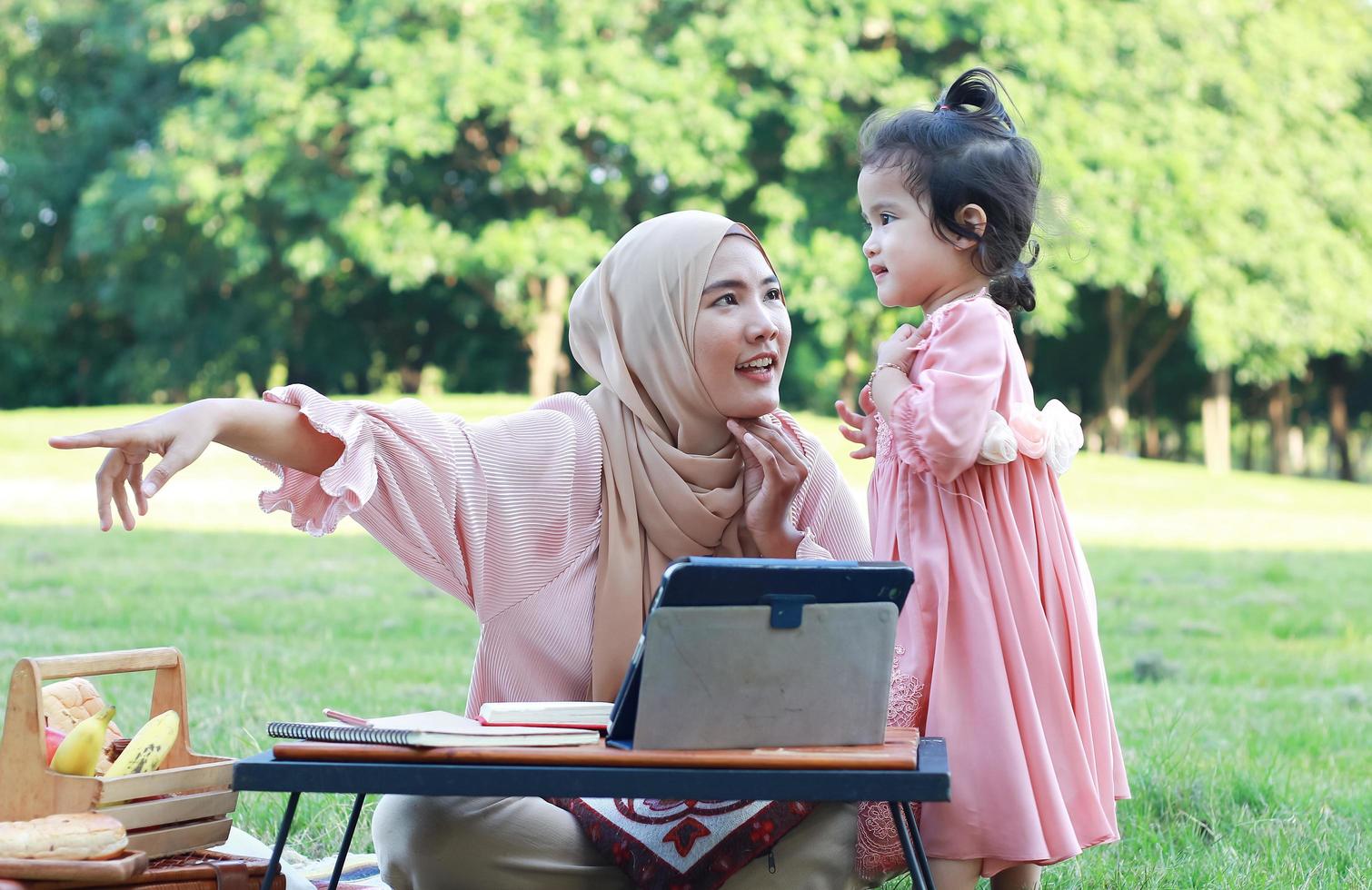 muslimska mödrar och döttrar njuter av sin semester i parken. kärlek och band mellan mor och barn foto
