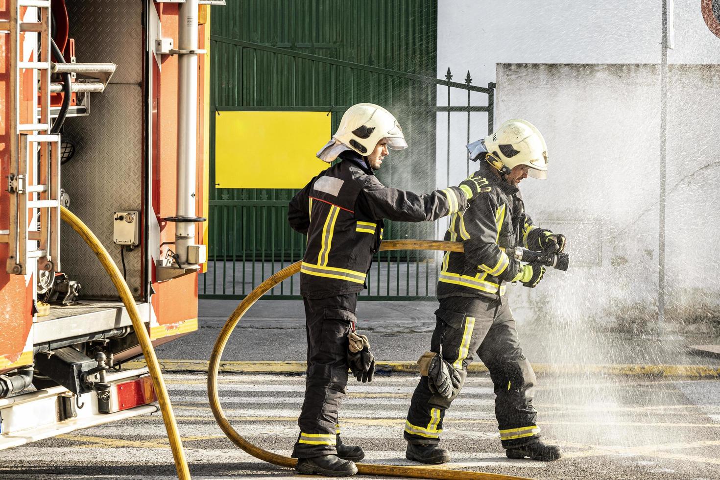 brandmän med en vattenslang som drar vatten för att släcka en brand foto