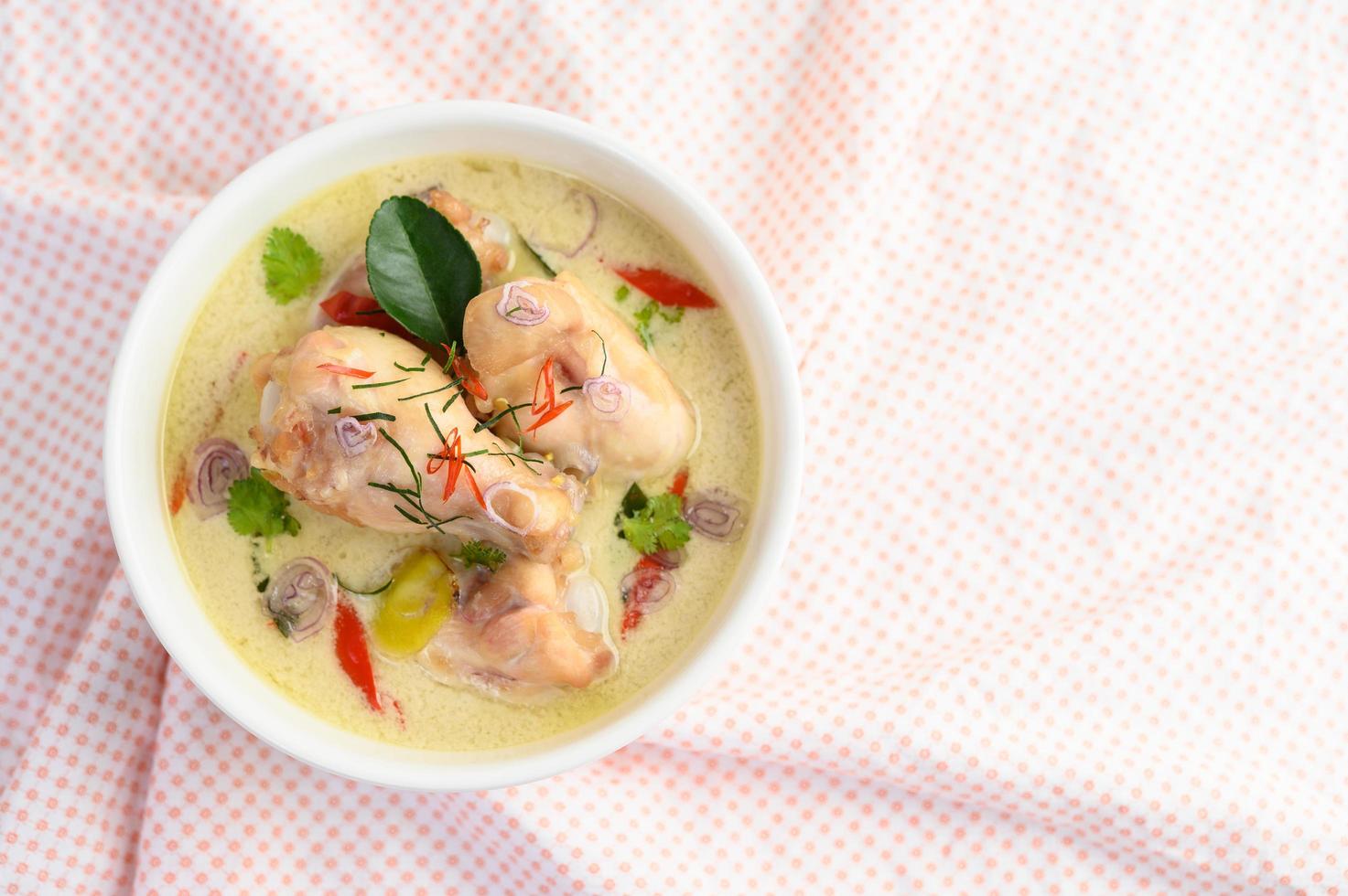 tom kha kai, thailändsk kokosnötsoppa på en rosa tyg foto