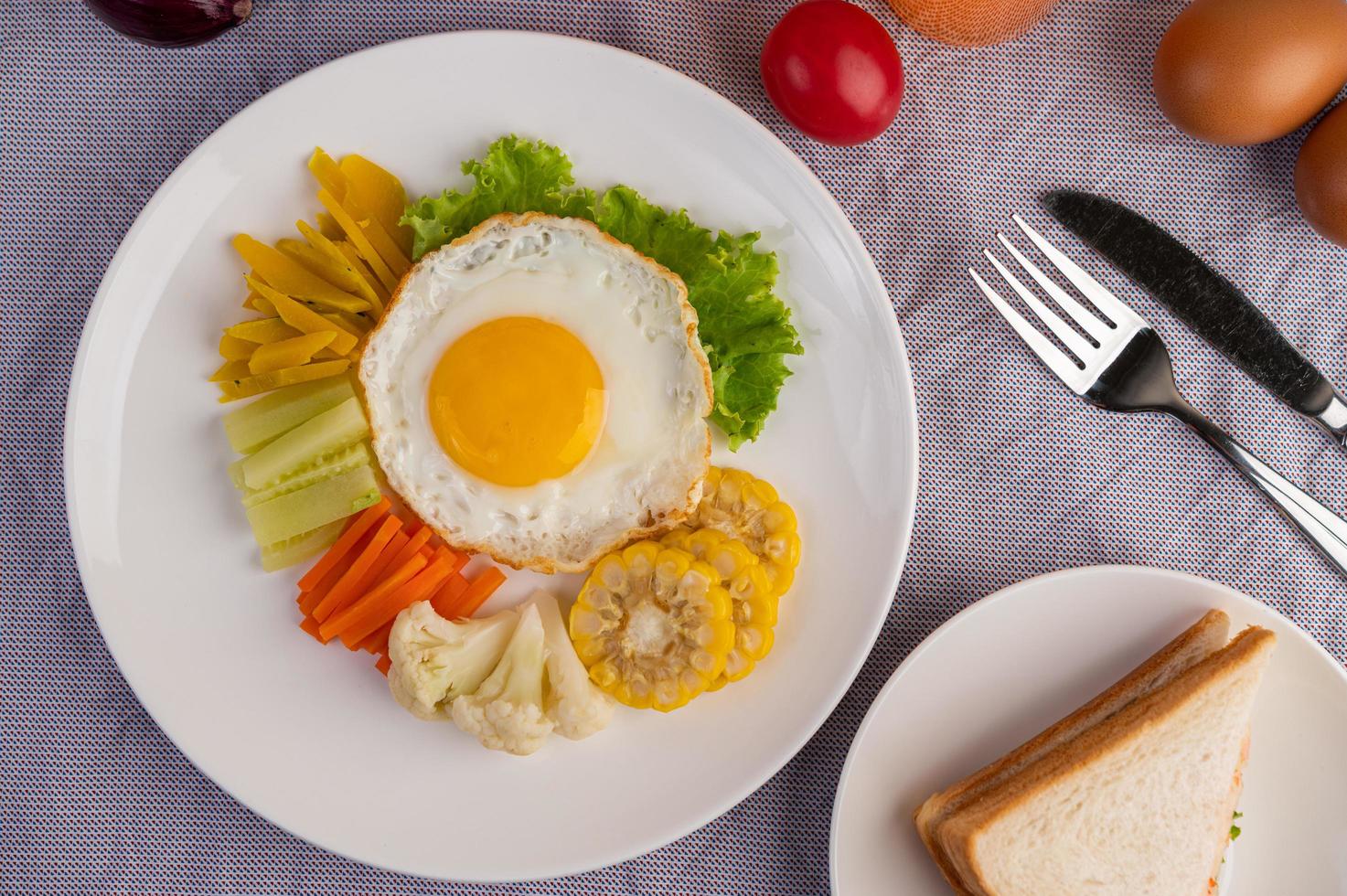 stekt äggfrukost med ägg, sallad, pumpa, gurka, morot och majs foto