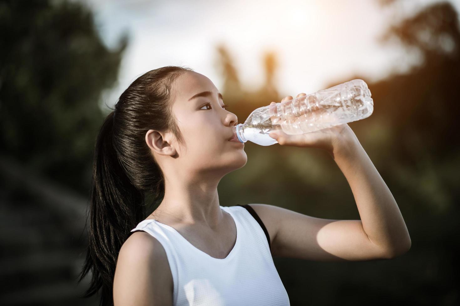 ung fitness tonåring dricksvatten efter att ha kört träning foto