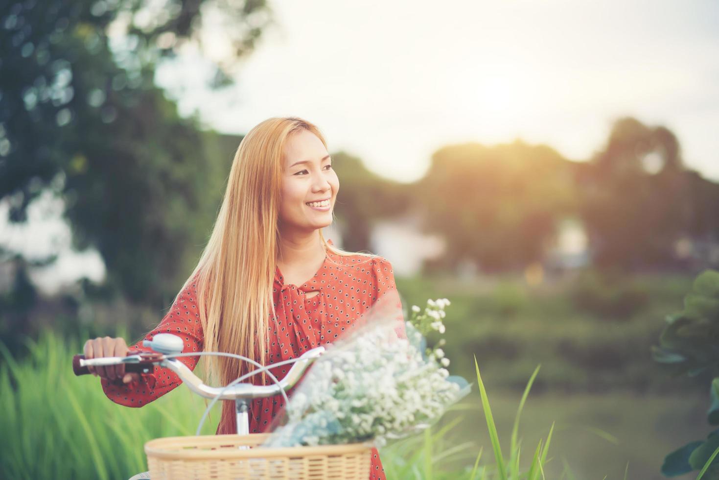 ung asiatisk kvinna som cyklar i en park foto