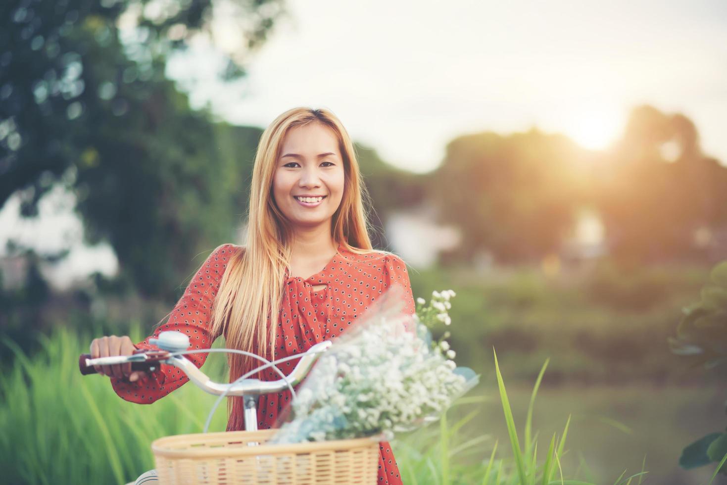 ung asiatisk kvinna som cyklar i en park foto