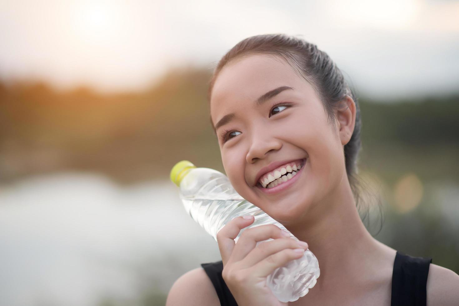 ung fitness tonåring håller vattenflaska efter att ha kört träning foto