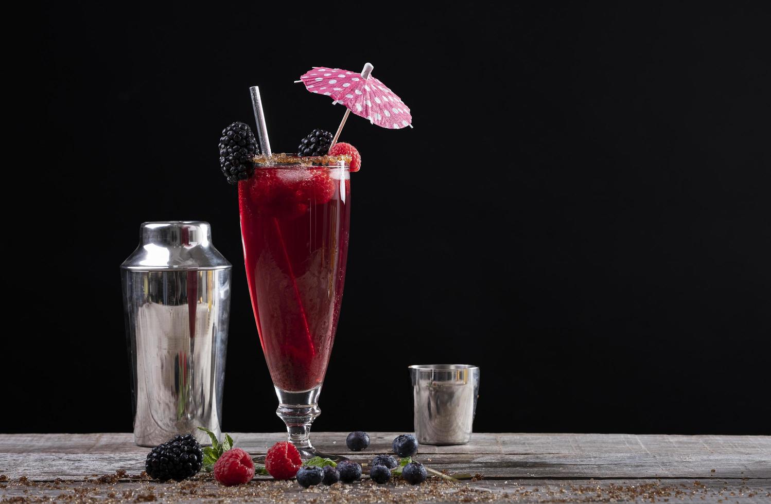 skogsfruktcocktail i ett glas på en träbas dekorerad med björnbär och en shaker foto