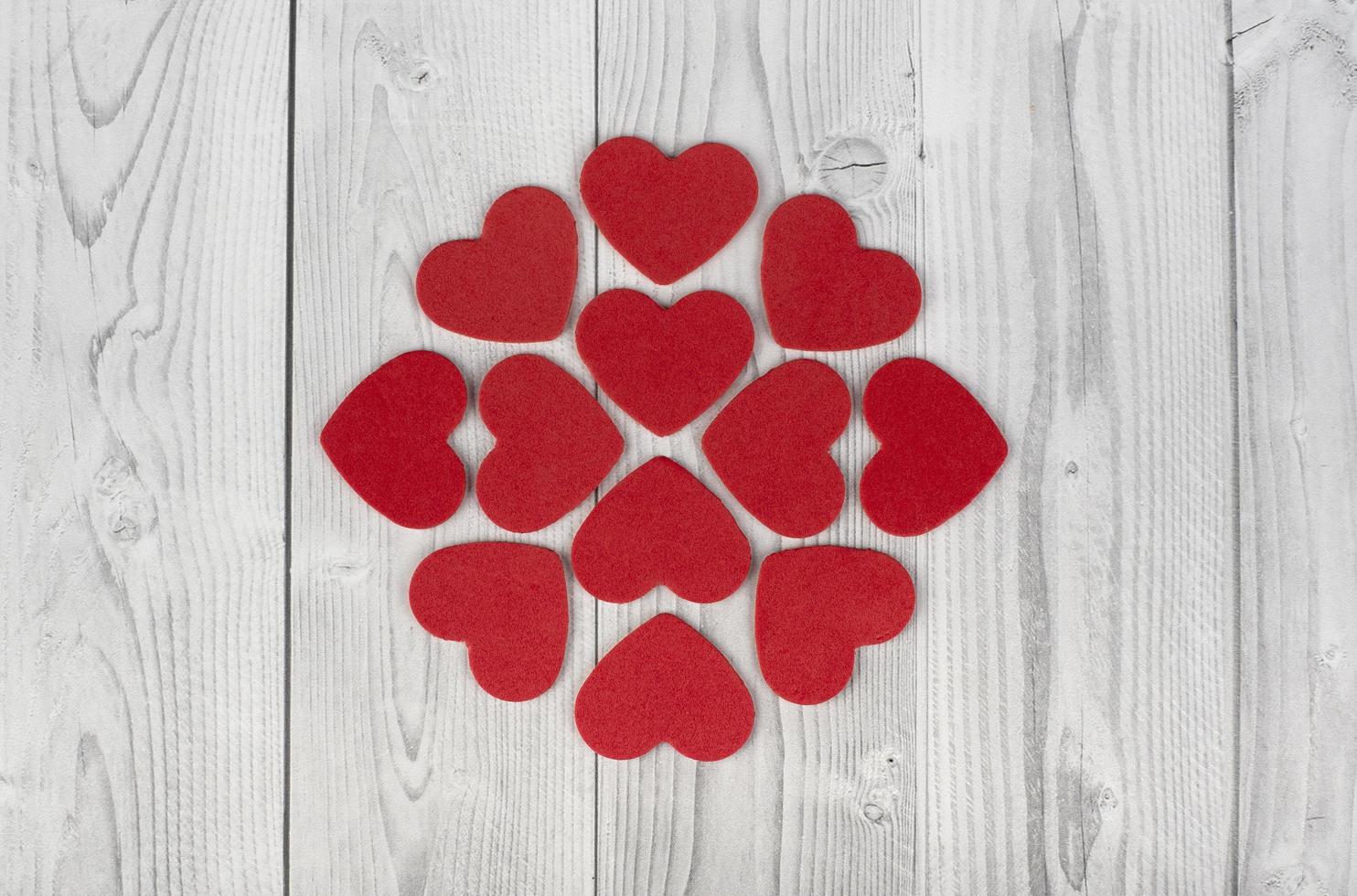 röda hjärtan som bildar en geometrisk figur i mitten av en vit och grå träbakgrund. begreppet alla hjärtans dag foto