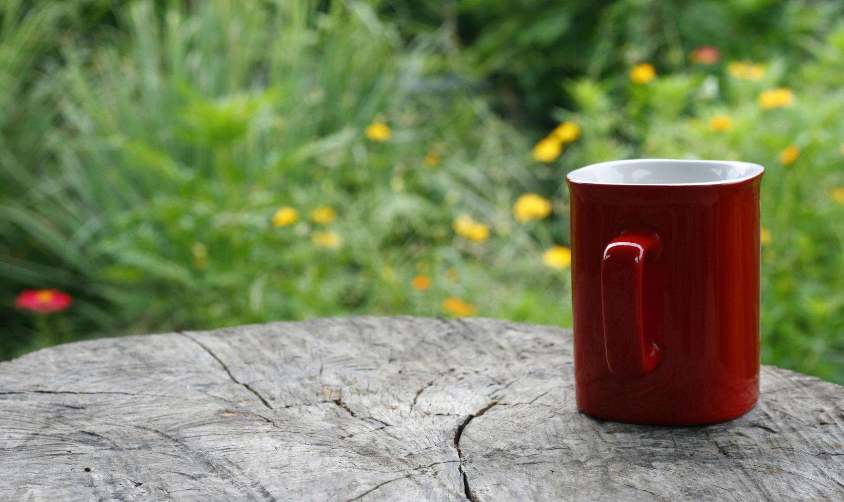 rött mugg kaffe på träplattan mot suddig grön foto