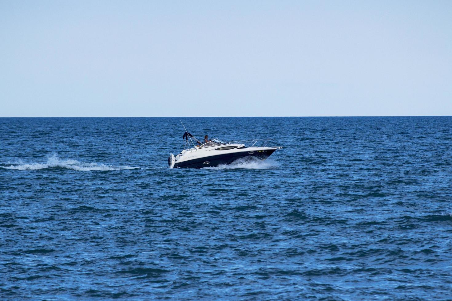 vit motorbåt på havet under dagtid foto