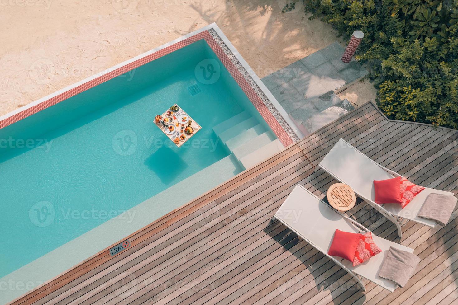 frukost i poolen, flytande frukost i lyxig tropisk resort. bord avkopplande på lugnt poolvatten, hälsosam frukost och fruktfat vid resortens pool. tropisk strand lyx livsstil foto