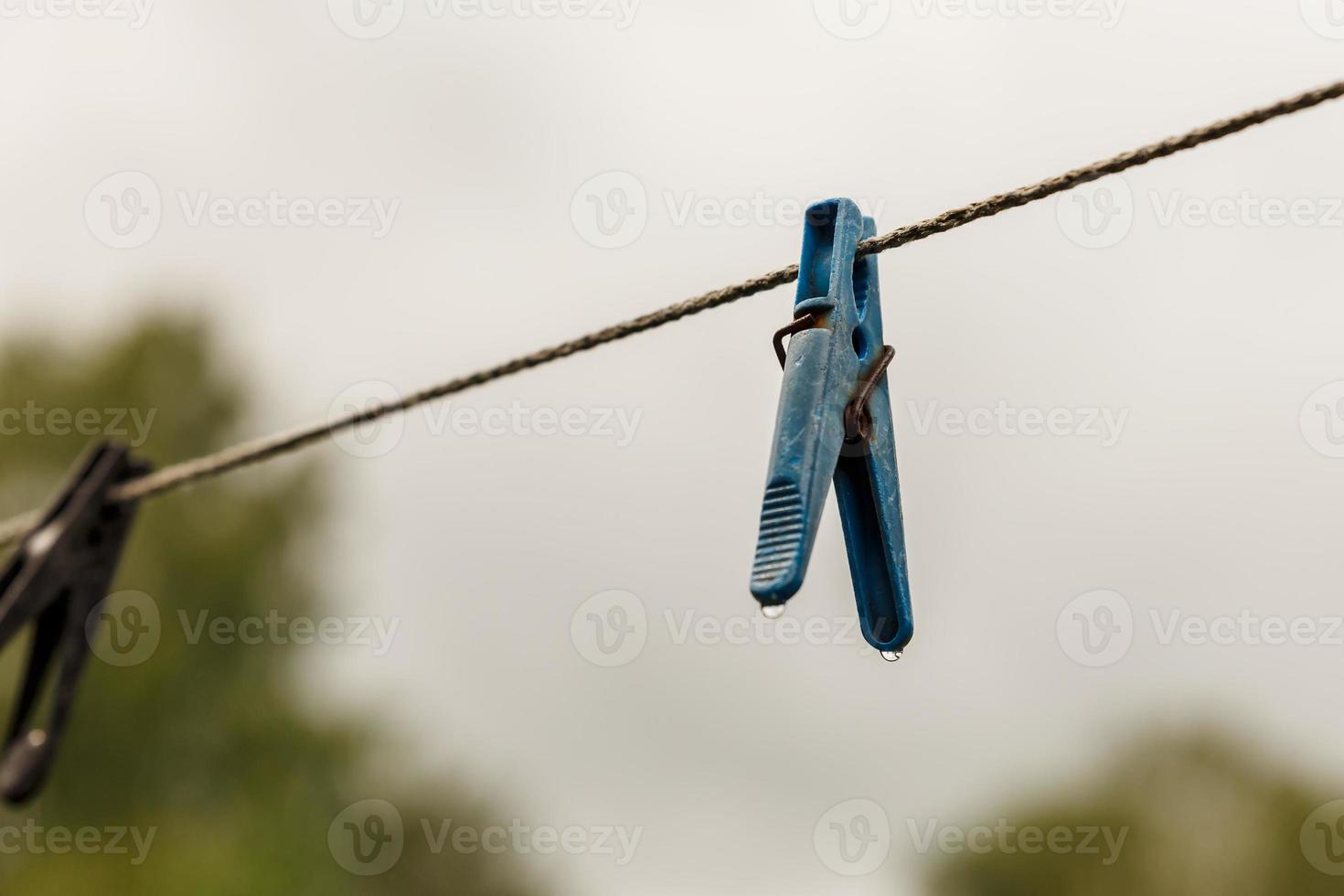 klädnypa hängande från en rep. en klädnypa hänger från de klädstreck. suddig bakgrund. foto