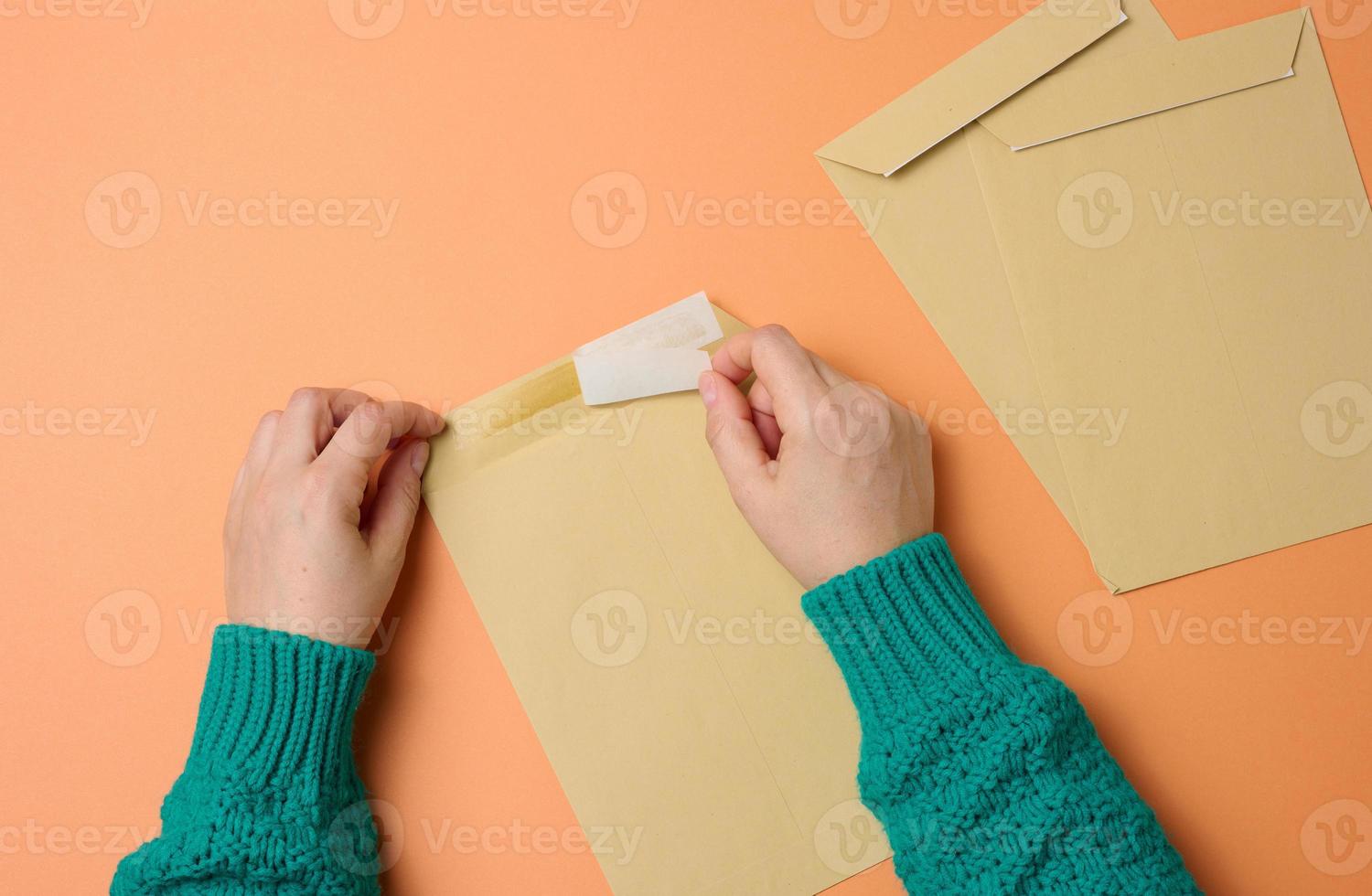 kvinna hand innehar papper kuvert på ett orange bakgrund, topp se. korrespondens foto