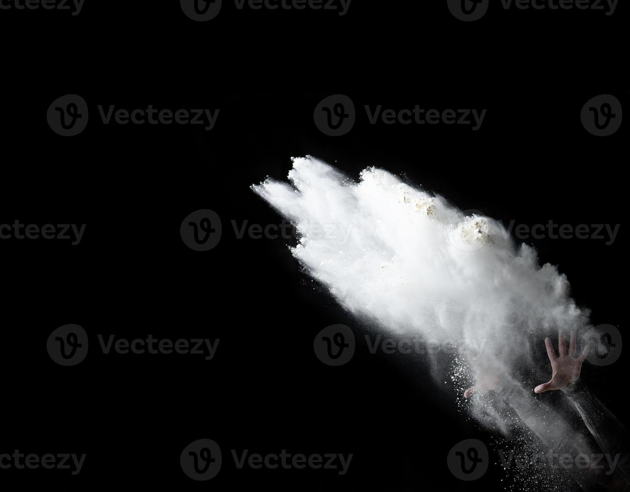 två kvinna händer kasta en näve av vit vete mjöl upp på en svart bakgrund foto