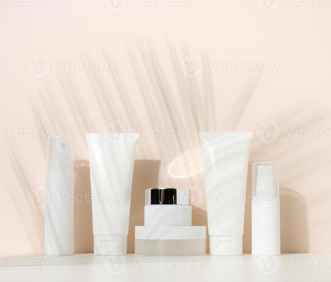 burk, flaska och tömma vit plast rör för kosmetika på en beige bakgrund. förpackning för grädde, gel, serum, reklam och produkt befordran foto