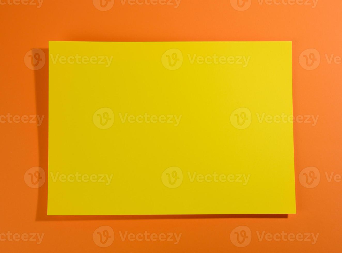 tom gul ark av papper på orange bakgrund med skugga foto