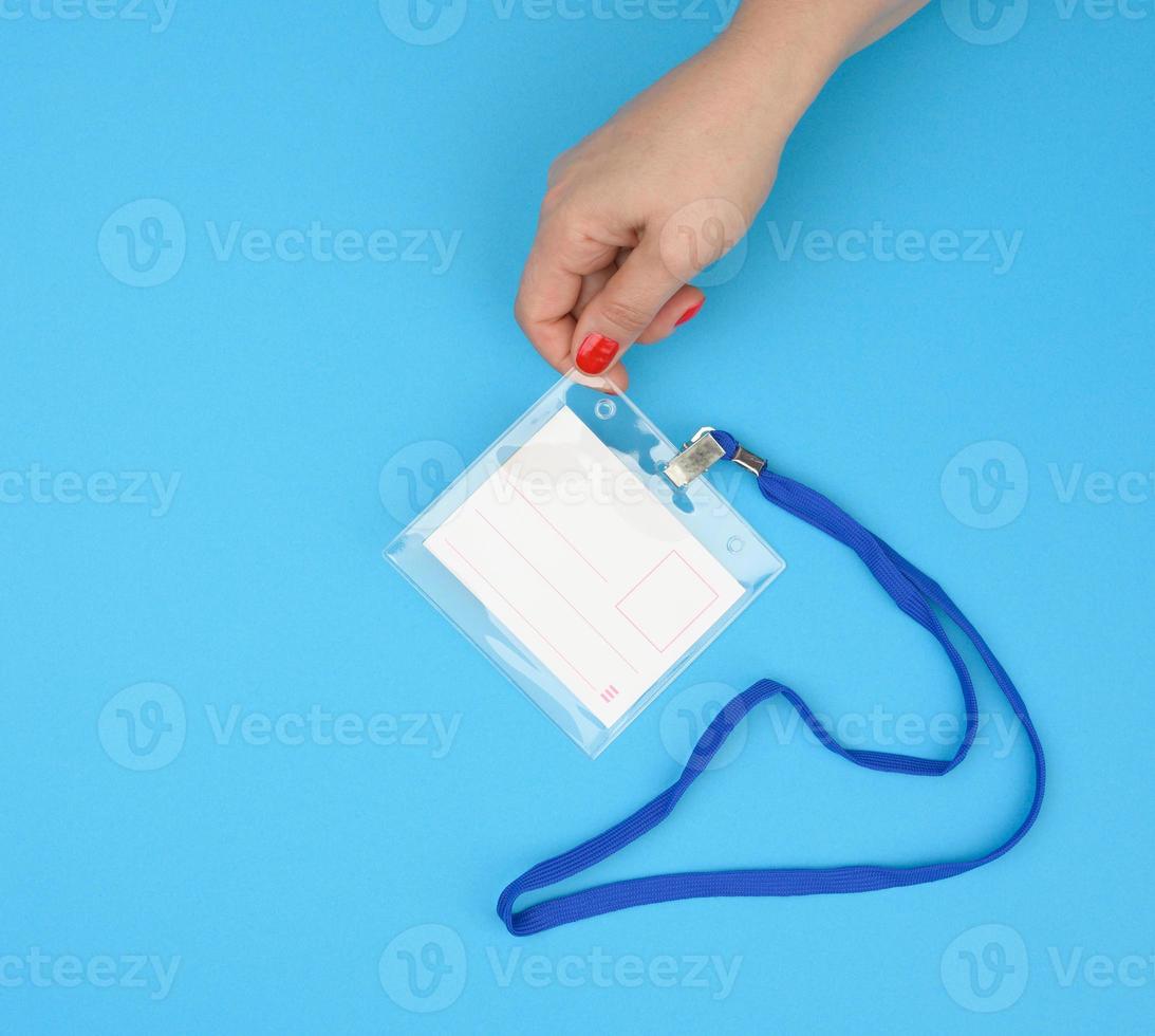 kvinna hand innehar transparent plast bricka på en blå snodd på en blå bakgrund foto