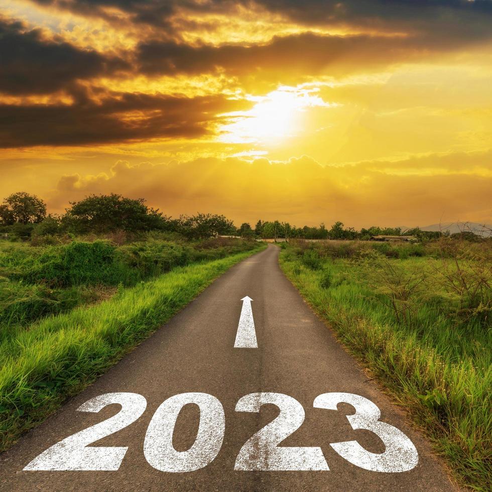 tömma asfalt väg och ny år 2023 begrepp. körning på ett tömma väg till mål 2023 med solnedgång. foto