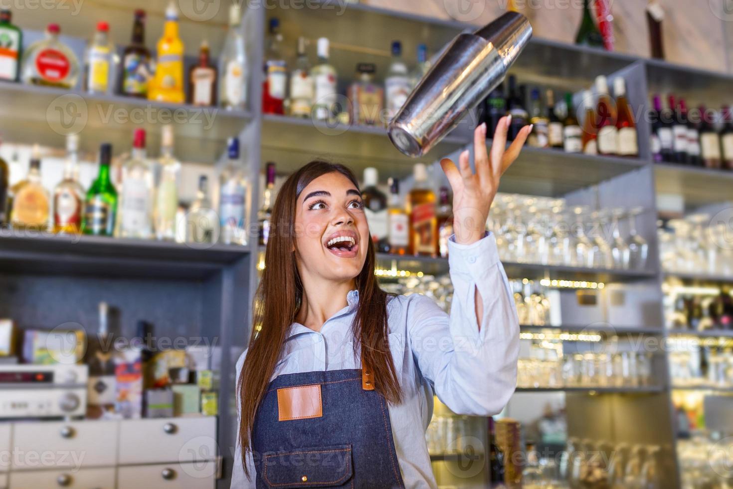 skön kvinna bartender kastar cocktails shaker in i de luft och ordnar en verklig visa för deras gäster foto