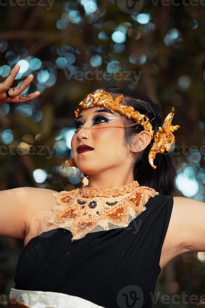 en skön javanese kvinna poser med henne hand i en svart kostym medan bär en gyllene krona och gyllene halsband foto