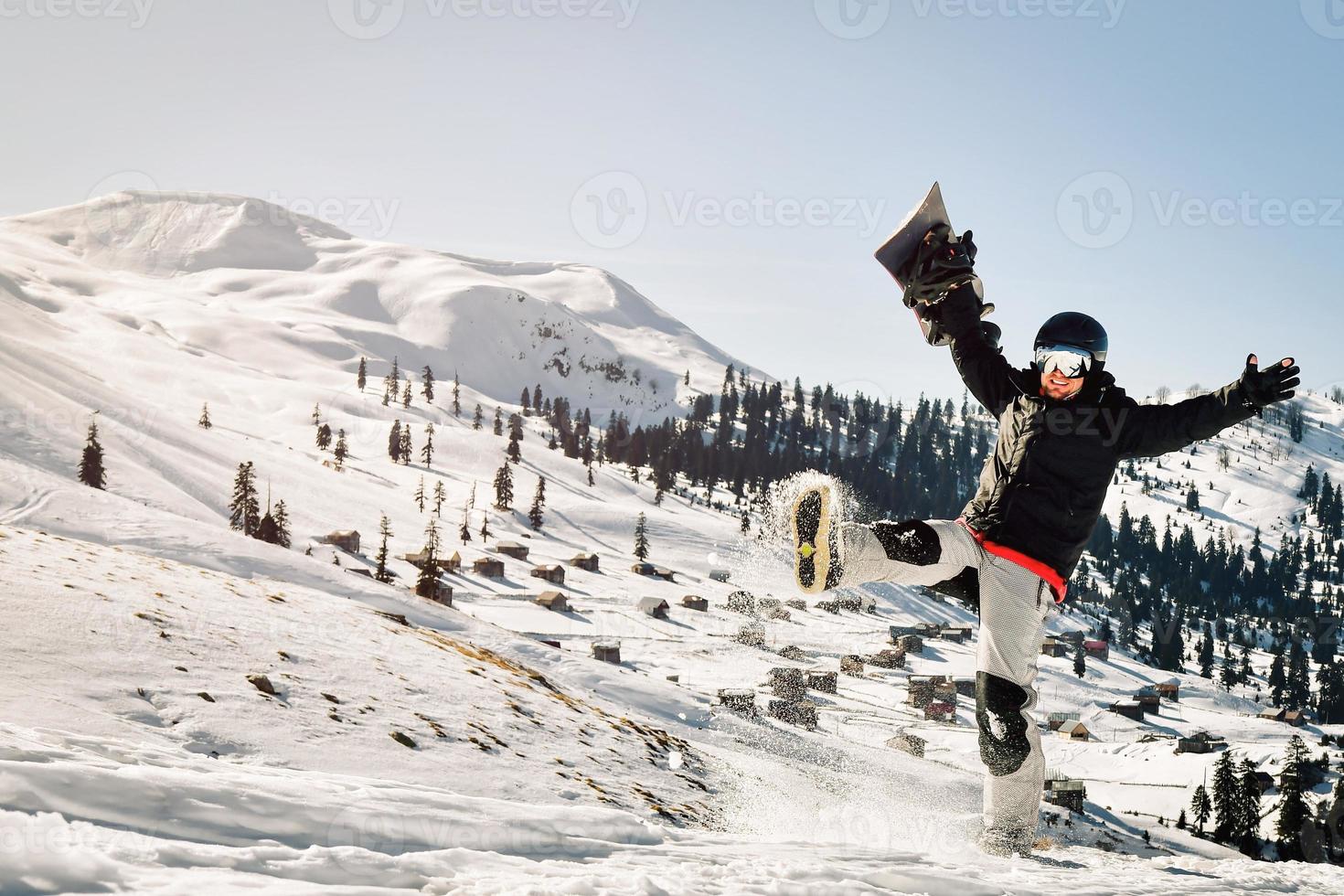 snowboardåkare innehav hans snowboard över huvud sparka snö Lycklig känsla bra i åka skidor tillflykt upphetsad på Semester semester solo. solig väder pulver dag foto