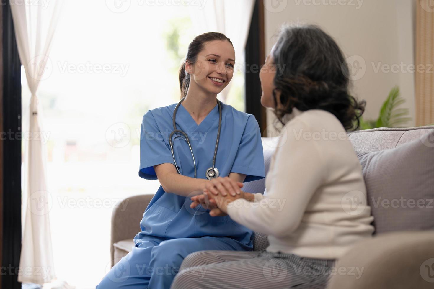 Lycklig patient är innehav vårdgivare för en hand medan utgifterna tid tillsammans. äldre kvinna i amning Hem och sjuksköterska. foto