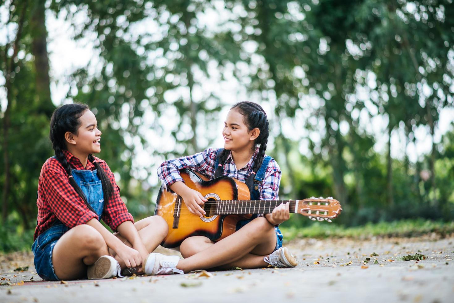 två flickor kopplar av och spelar gitarr foto