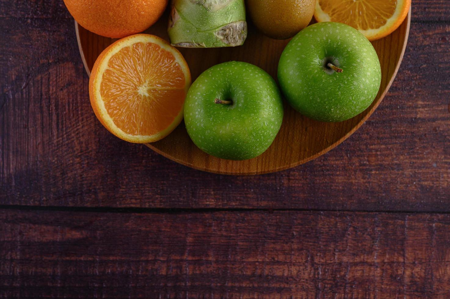 apelsinskivor med äpple, kiwi och broccoli på en träplatta foto