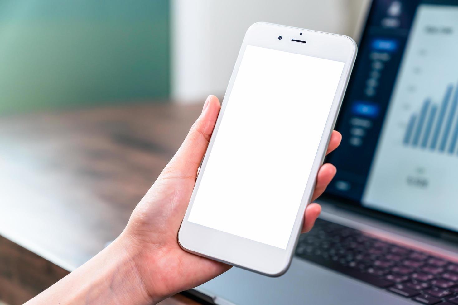 hand som håller smartphone-mockup av den tomma skärmen på bordet foto