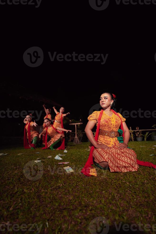 en grupp av indonesiska dansare utför på de skede med en röd scarf och traditionell orange klänning inuti de festival foto