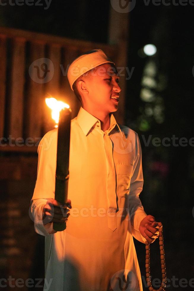 en muslim man innehav en brand ficklampa på de campingplats i de by foto