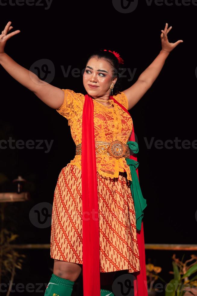 ett asiatisk traditionell dansare i ett orange klänning med en röd scarf och smink utför på de dansa festival foto