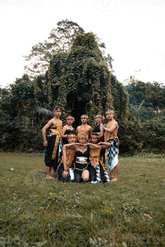 en grupp av balinesisk människor poser tillsammans med en Lycklig ansikte medan bär gyllene kostymer efter de prestanda foto