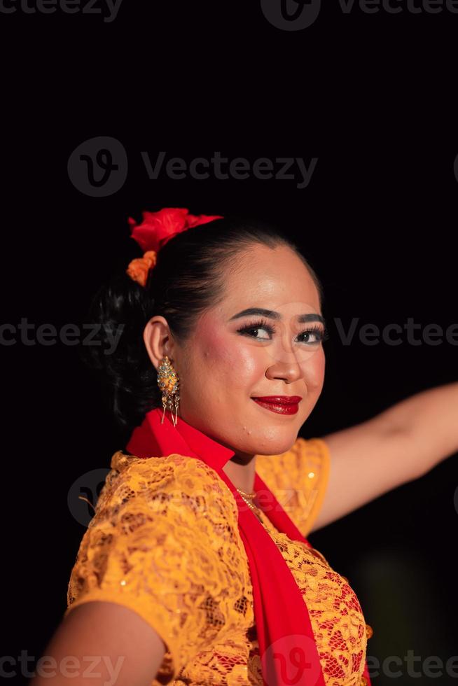 närbild ansikte av en balinesisk kvinna under de traditionell dansa prestanda medan bär ett orange kostym och smink foto