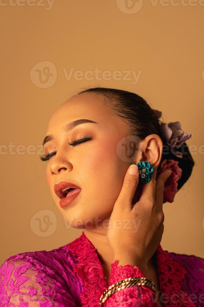 sexig asiatisk kvinna bär en rosa klänning kallad kebaya med en varm utgör foto